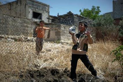 Ein Kind spielt mit den Überresten einer Mörsergranate, die die israelische Armee im Juni 2026 bei einem Überfall auf ein Dorf in der Provinz Daraa nahe der syrisch-jordanischen Grenze abgefeuert hatte. Ein Anwohner erzählte, als er israelische Soldaten fragte, warum sie seine Enkel im Teenageralter festnahmen, hätten diese geantwortet: „Die Kinder reden einfach zu viel.“ (Bildnachweis: Omar Sanadiki/AP)